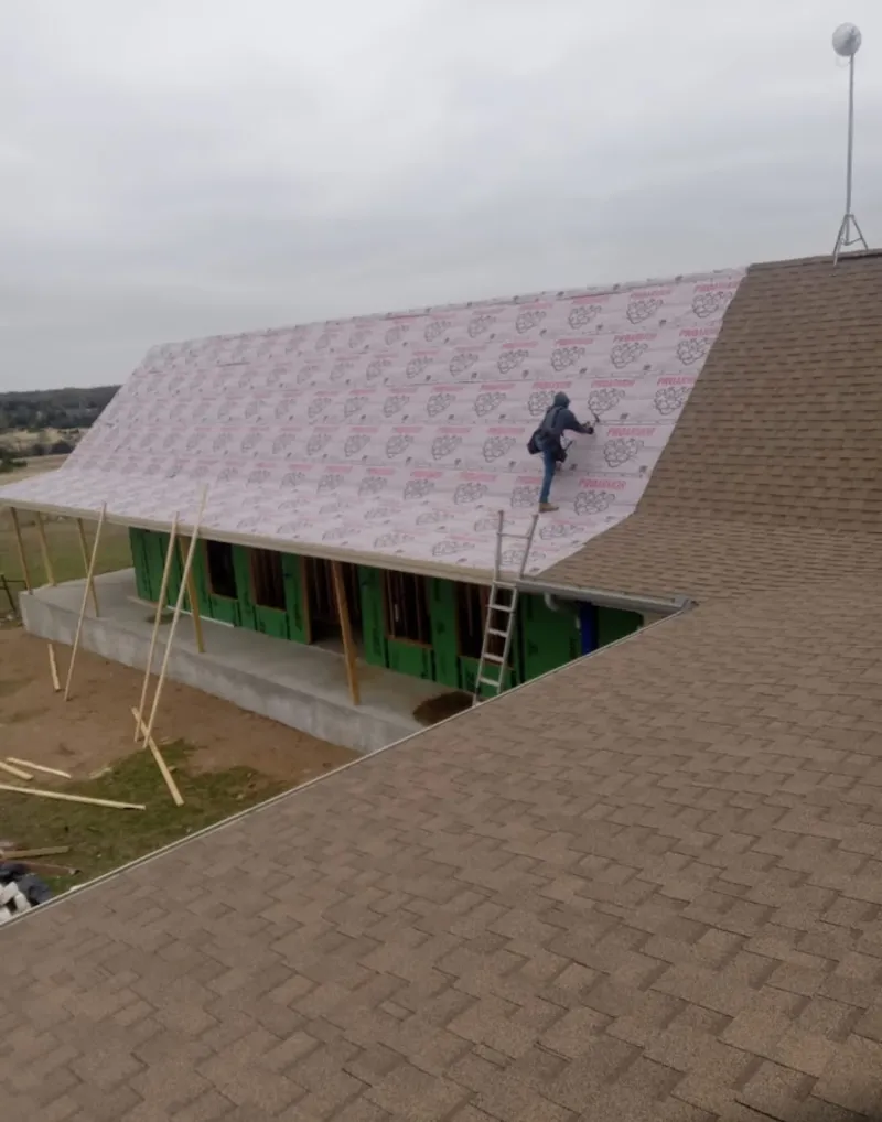 Worker preparing underlayment for a metal roof installation in Paxton